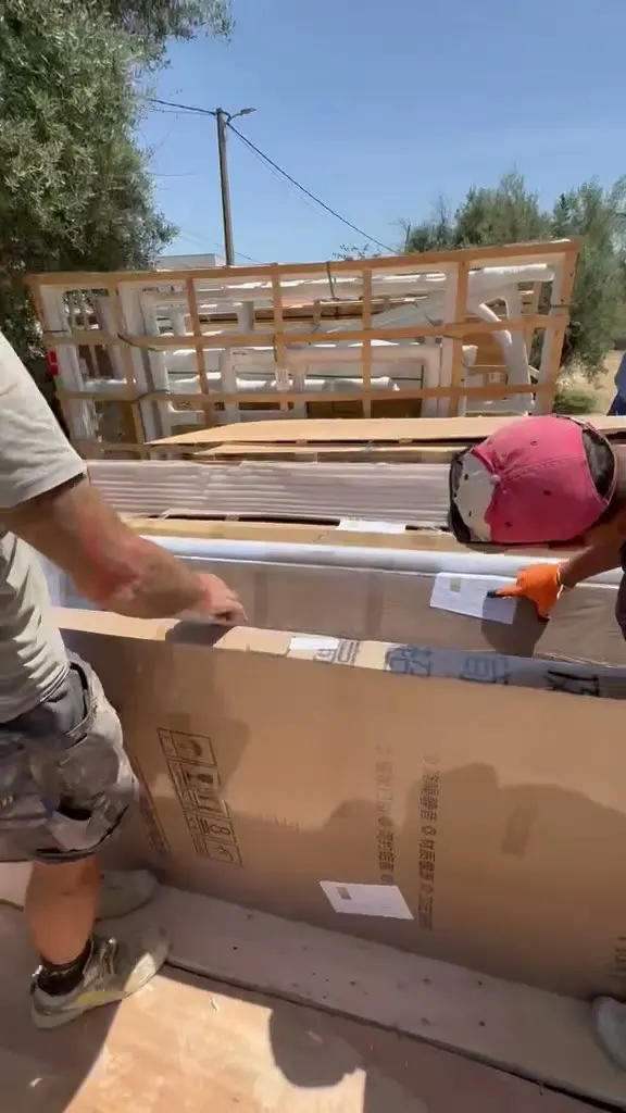 Packaged doors and windows being handled at the completed Spain residential delivery stage.